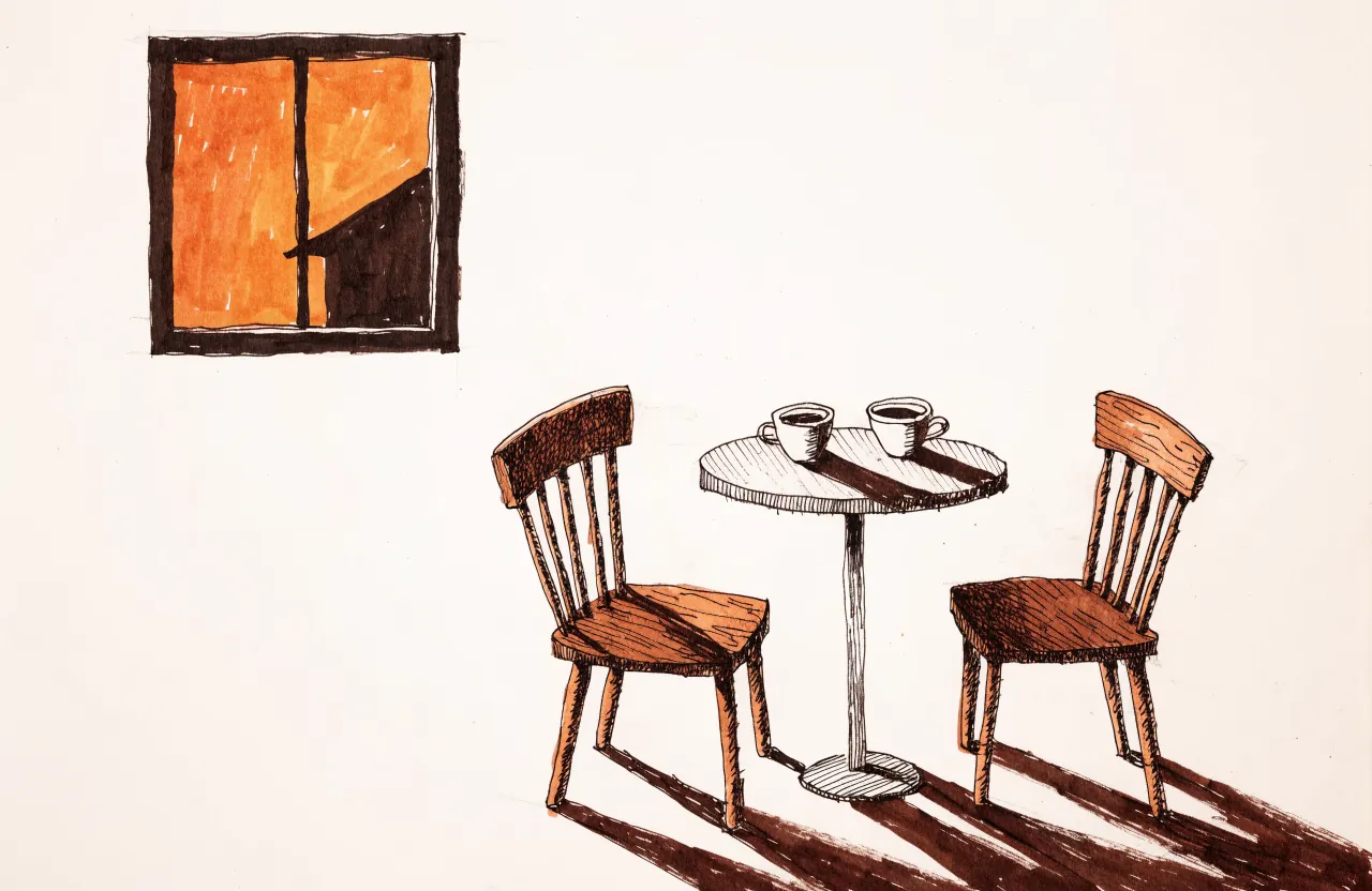 Two wooden chairs facing each other across a small round table with two cups